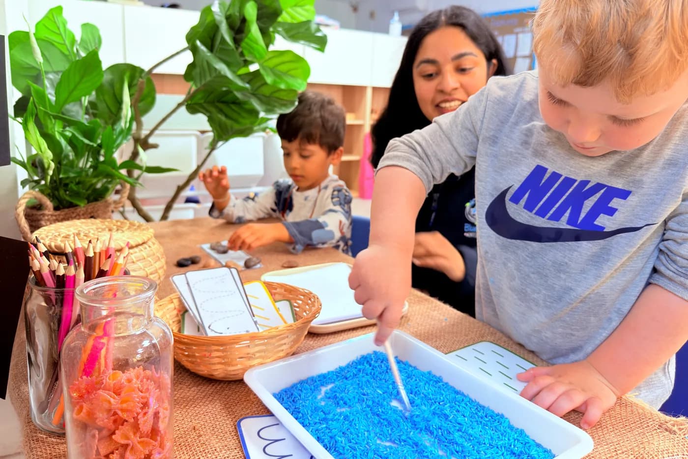 Child mark-making in the blue sensory writing tray at Blue Nest Montessori Borehamwood