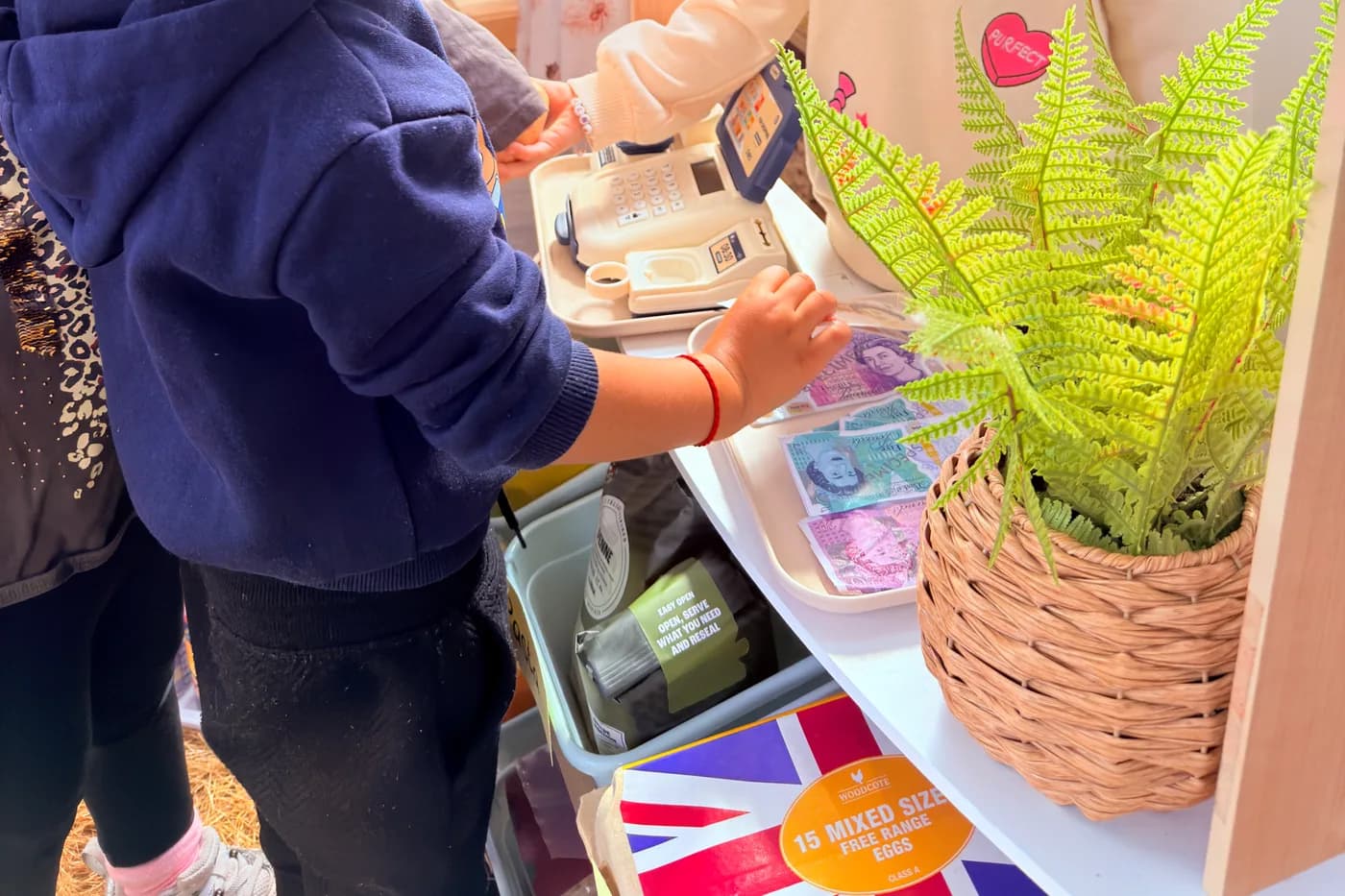 Children playing at the role-play market stall at Blue Nest Montessori Borehamwood