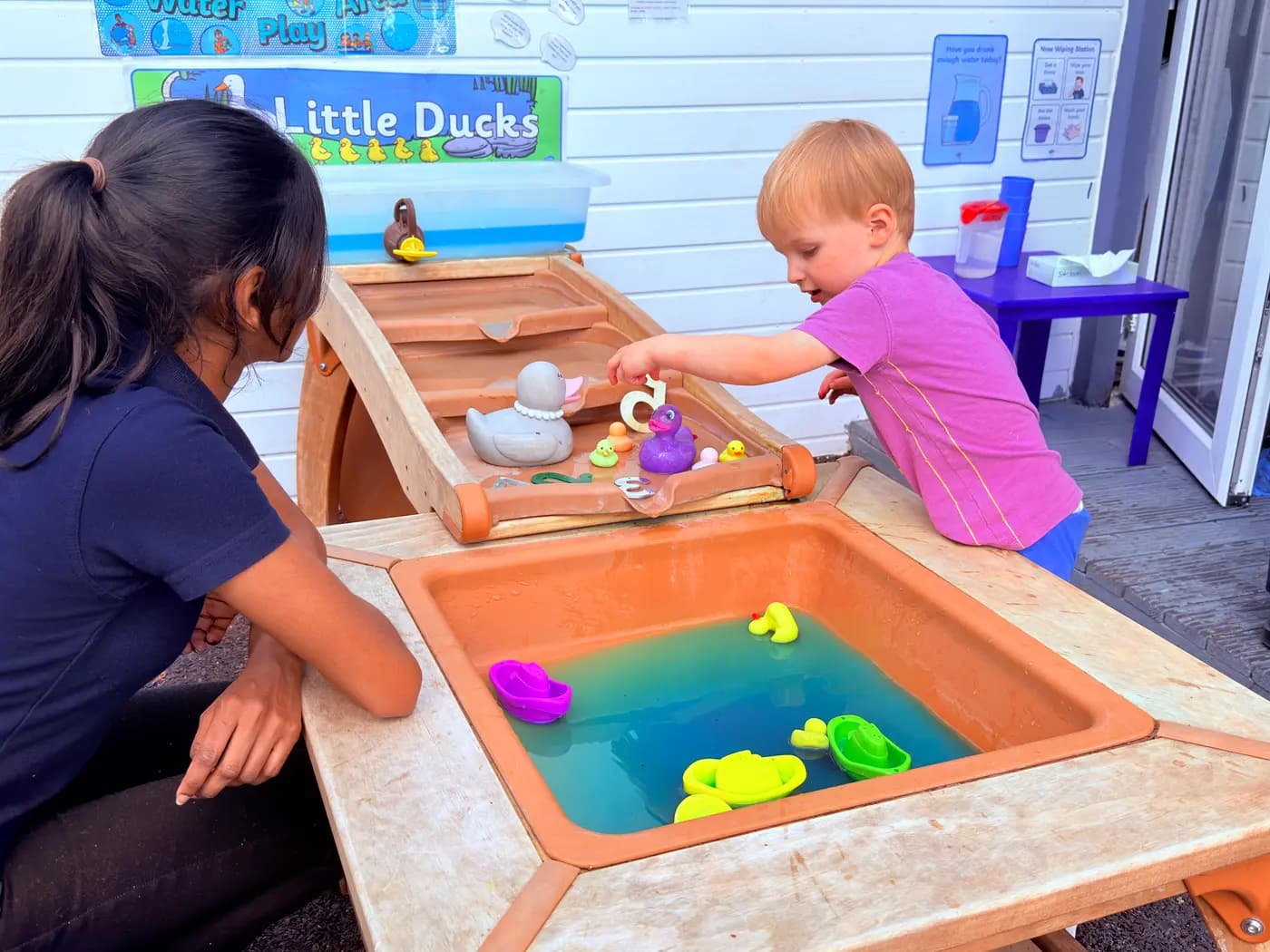 Children enjoying outdoor water play at Blue Nest Montessori Harrow
