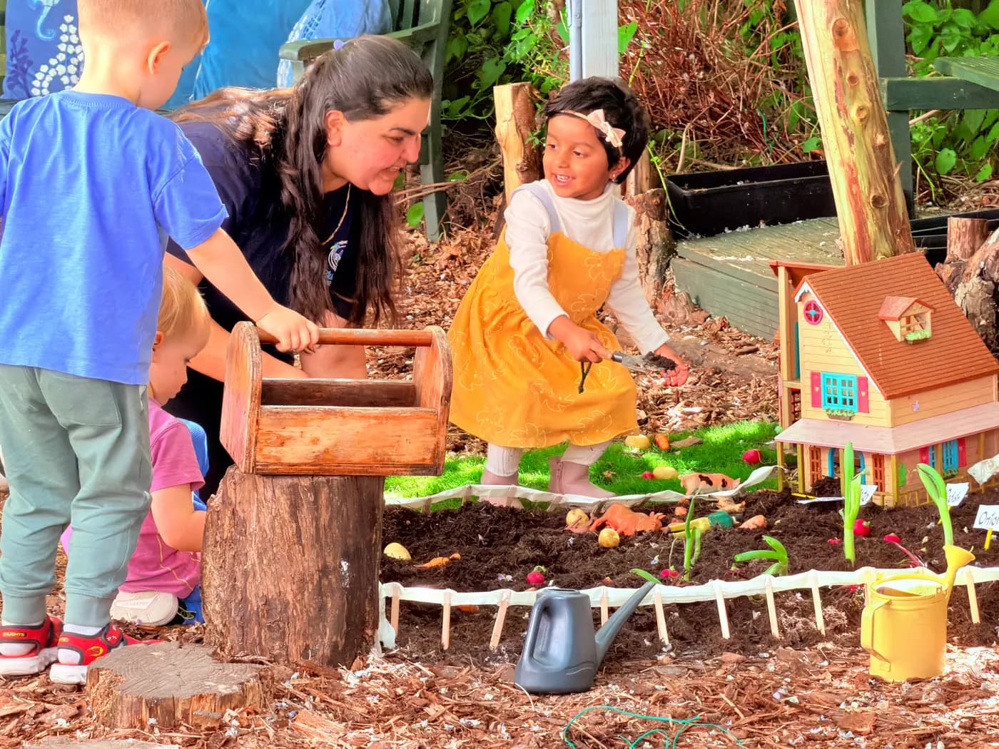 Children gathered around an outdoor activity table in the Blue Nest Montessori Harrow garden
