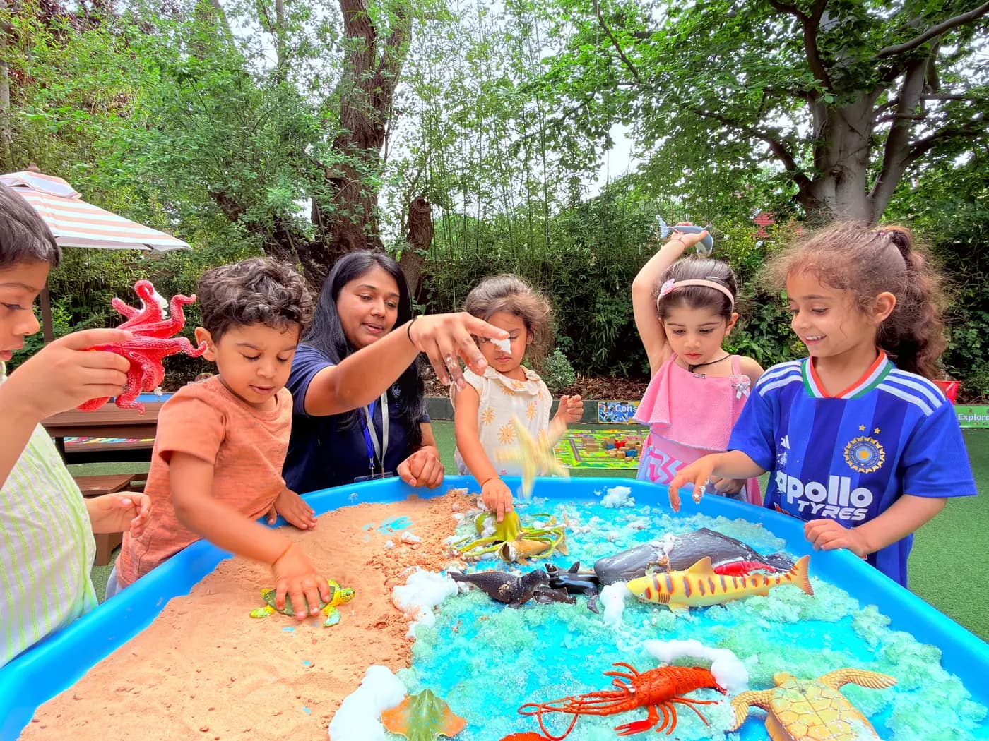 Children at an outdoor floor activity on a colourful mat at Blue Nest Pinner