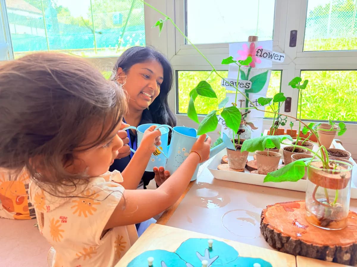 An educator and child watering bean plants at a nature and plant-growing activity at Blue Nest Pinner