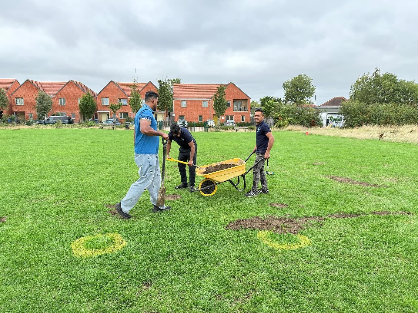 Volunteers with a wheelbarrow and spade filling holes on the green