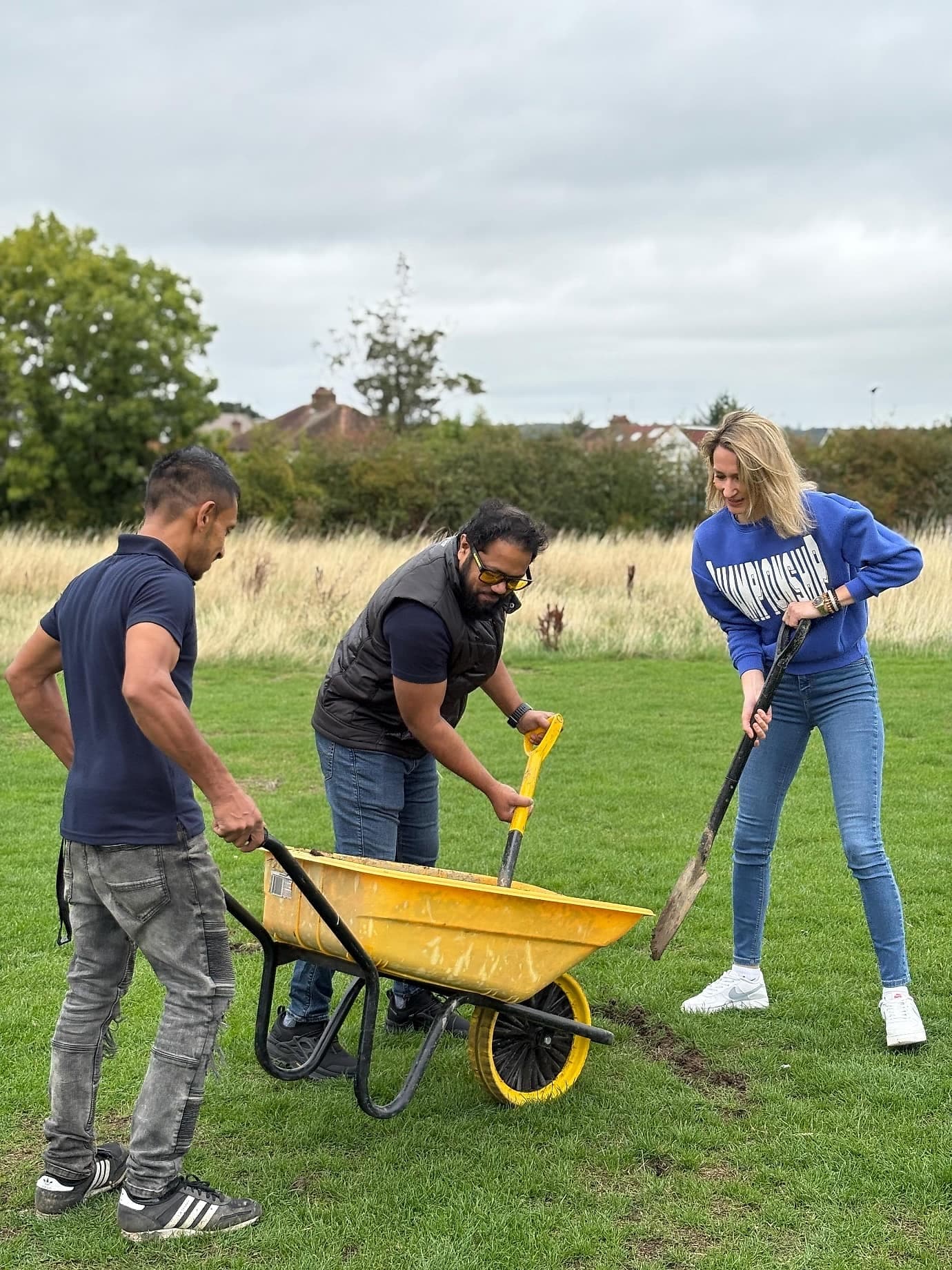 Volunteers wheeling soil across the green